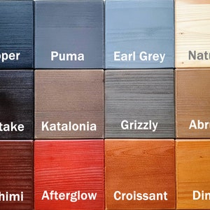 May include: A wood stain color chart with 12 different wood stain colors. The colors are: Pepper, Puma, Earl Grey, Natural, Shiitake, Katalonia, Grizzly, Abruzzo, Sashimi, Afterglow, Croissant, and Dingo.