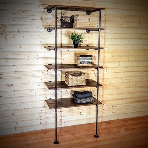 May include: A six-shelf industrial pipe and wood shelf unit with a rustic brown finish. The shelves are filled with various items, including a small iron object, a potted plant, books, a wicker basket, and folded fabric.