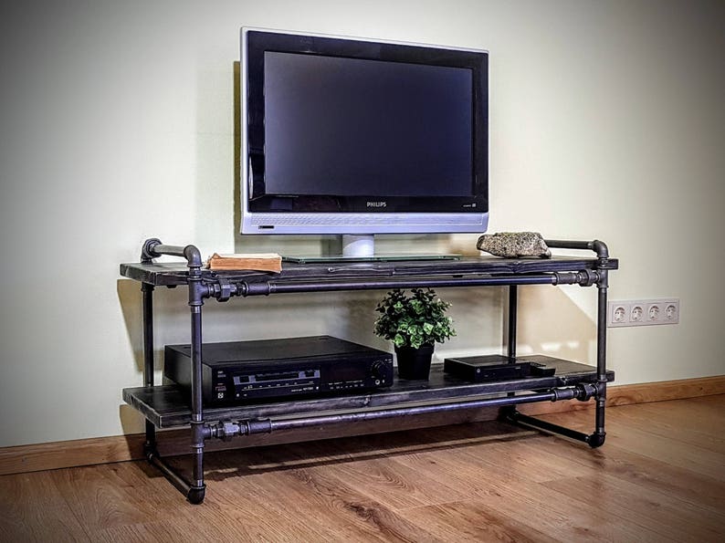 May include: A black metal TV stand with two shelves. The stand has a black metal frame and black wooden shelves. A flat screen TV, a DVD player, and a potted plant are on the shelves.