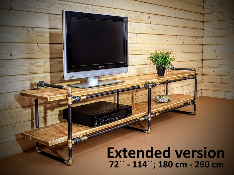 May include: A black metal and wood TV stand with two shelves. The stand is 72" to 114" long, or 180 cm to 290 cm.  The stand is made of black metal pipes and wooden shelves.  The stand is shown in an extended version.