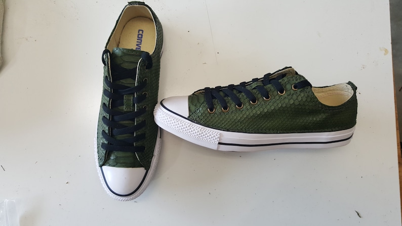 May include: A pair of green leather Converse trainers with black laces. The trainers have a snakeskin pattern.