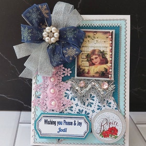 Personalizowana kartka Wesołych Świąt. Srebrnoniebieska kartka Silent Night z wstążkami, broszką, koronką i mnóstwem pereł.