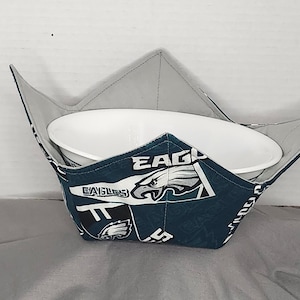 Könnte beinhalten: Ein tealfarbener und weißer Stoff-Schüsselwärmer mit dem Philadelphia Eagles Logo und dem Wort "Eagles". Der Wärmer ist so konzipiert, dass er eine Schüssel hält und warm hält.