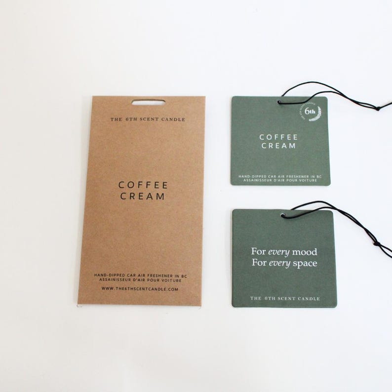 Puede incluir: Dos ambientadores de coche verdes con el texto "Coffee Cream" y "For every mood, For every space" y el logotipo "The 6th Scent Candle".