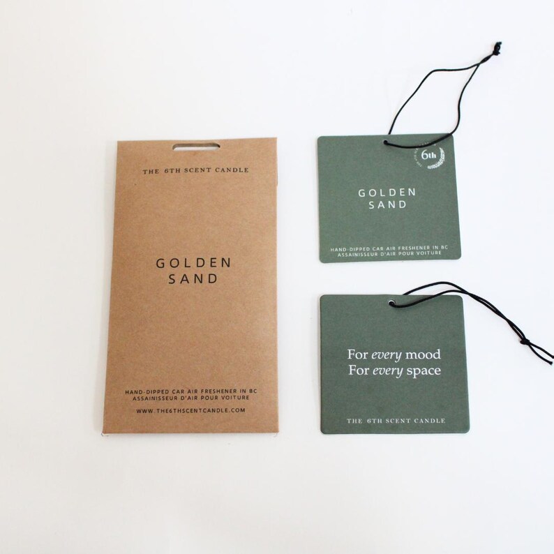 Puede incluir: Un conjunto de tres ambientadores para coche en envases marrones y verdes. Los ambientadores est&aacute;n hechos a mano y tienen el aroma "Golden Sand". El envase incluye el texto "The 6th Scent Candle" y "For every mood, For every space".