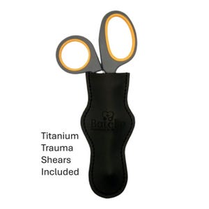 Op de afbeelding: Grijze en oranje titanium traumaschaar met een zwarte leren schede. De schaar heeft oranje accenten op de vingergaten en bladen. De tekst "Titanium Trauma Shears Included" is zichtbaar.