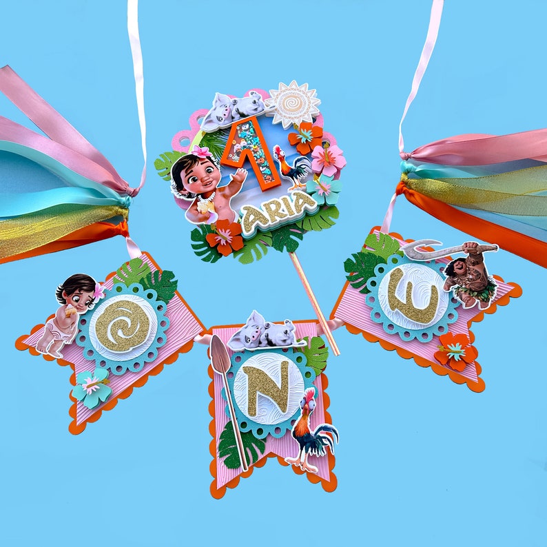 Puede incluir: Una pancarta de cumplea&ntilde;os de Moana rosa y azul con la palabra "ONE" en letras doradas con purpurina. La pancarta tambi&eacute;n presenta un cerdo, un gallo y una flor. La pancarta es perfecta para una fiesta de primer cumplea&ntilde;os.