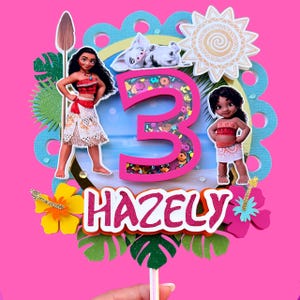Puede incluir: Un vibrante adorno para pastel con el nombre "HAZELY" y el n&uacute;mero "3" con un elemento agitador. El dise&ntilde;o incluye ilustraciones de personajes de la pel&iacute;cula Moana, junto con flores tropicales y un sol. El fondo es rosa brillante.