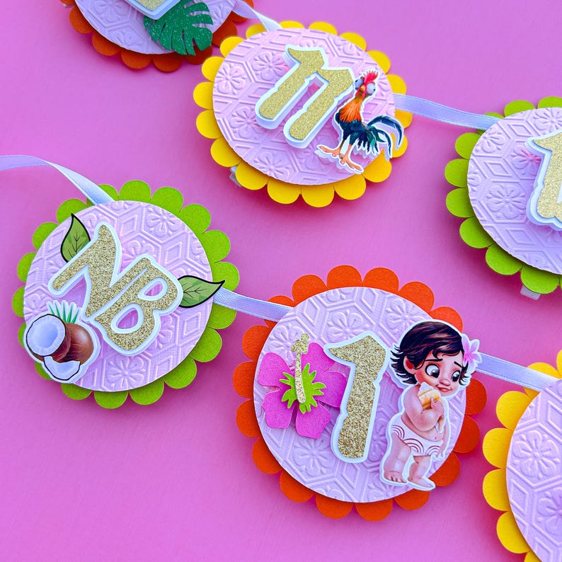 May include: A pink and green banner with a pink background and a white ribbon. The banner has six circles with different designs. The circles have a pink background with a white pattern. The circles have gold numbers, a rooster, a coconut, a butterfly, and a cartoon character. The banner says "NB 1"