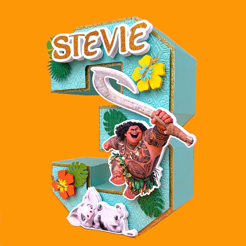 Puede incluir: Un adorno para tarta con el n&uacute;mero 3 en color turquesa con el nombre "Stevie" en purpurina dorada. El adorno presenta una imagen de dibujos animados de Maui de Moana sosteniendo su anzuelo, junto con Pua y una flor de hibisco amarilla.