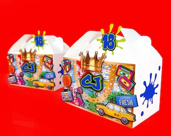 Puede incluir: Dos cajas de cartón blanco para favores de fiesta con gráficos coloridos. Las cajas presentan una corona dorada, un "CJ" estilo graffiti, un taxi amarillo y el texto "California Fresh". Las cajas también tienen un diseño de salpicaduras de pintura azul y el número "18" en la parte superior.