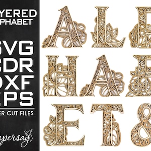 May include: Layered alphabet letters A, L, P, H, A, B, E, T, and & in a gold color with intricate floral designs. The letters are layered and have a 3D effect. The letters are suitable for laser cutting.