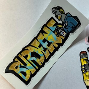 May include: A sticker with a cartoon bird holding a cup of coffee and the word "BIRDMEN" in yellow and blue graffiti style.