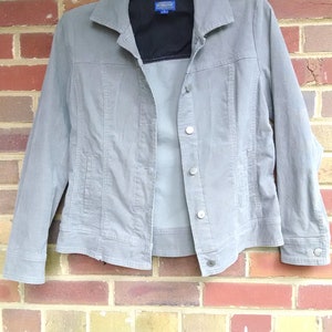 May include: A gray denim jacket with a black lining and a blue Pendleton label. The jacket has a button closure and two pockets.