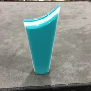 May include: A teal and white decorative vase with a flared top. The vase has a glossy finish and a modern, minimalist design. The vase is approximately 6 inches tall.