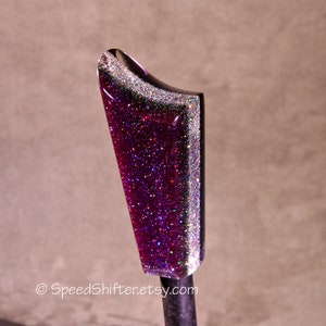 May include: A custom-made, glitter-infused shift knob. The knob features a deep purple base with silver glitter accents along the edges. The top is black and curved. The Etsy shop name, SpeedShifter.etsy.com, is visible at the bottom.