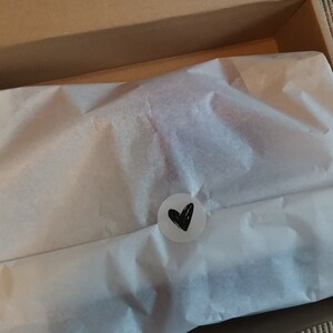 Packaging of the slippers. It is packed in a box with white silk paper and a sticker with a heart