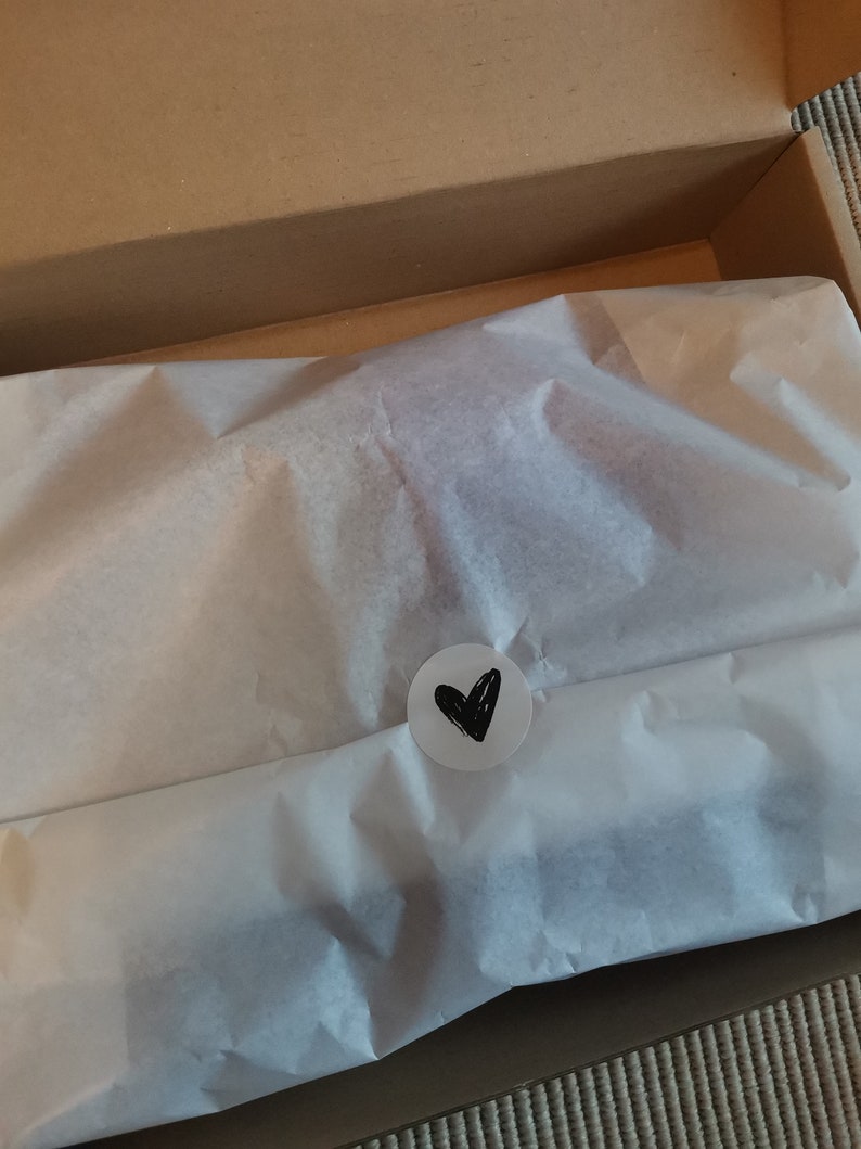 Packaging of the slippers. It is packed in a box with white silk paper and a sticker with a heart