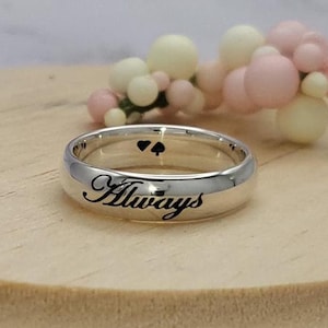 May include: A silver band ring with the word "Always" engraved on the outside and two small hearts engraved on the inside.
