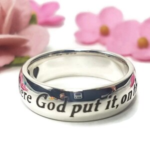 May include: A silver ring with the inscription "Where God put it, on the", a popular saying for wedding bands.