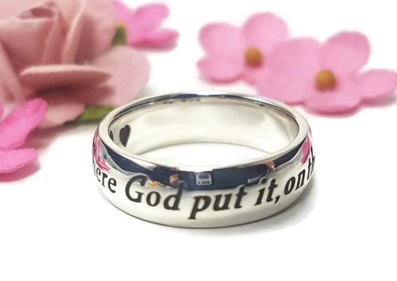 May include: A silver ring with the inscription "Where God put it, on the", a popular saying for wedding bands.