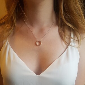 Puede incluir: Un collar de cadena de plata con un simple colgante circular.