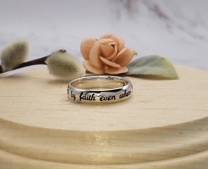 Puede incluir: Un anillo de banda de plata con la inscripci&oacute;n "Camino por fe incluso cuando no puedo ver" grabada alrededor de la banda.