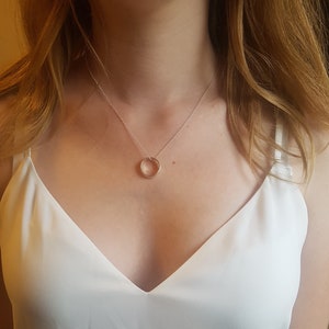 May include: A silver chain necklace with a simple circle pendant.