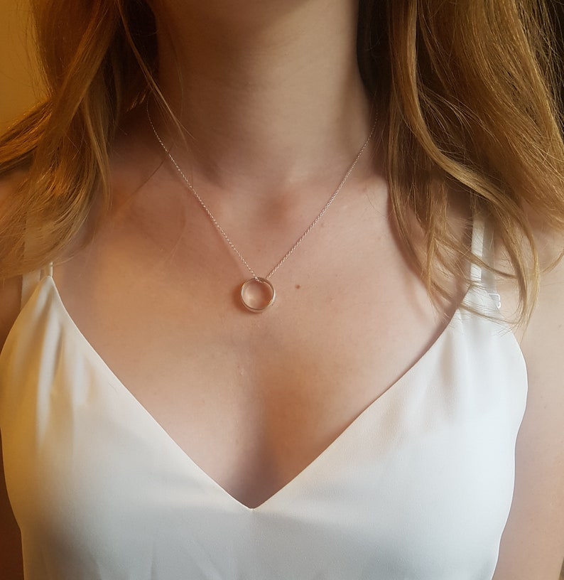 May include: A silver chain necklace with a simple circle pendant.