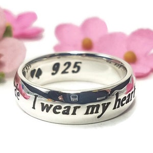 May include: A silver ring with the inscription "I wear my heart on my sleeve" and the number "925" on the inside of the band.