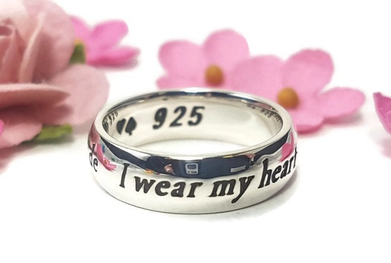 May include: A silver ring with the inscription "I wear my heart on my sleeve" and the number "925" on the inside of the band.