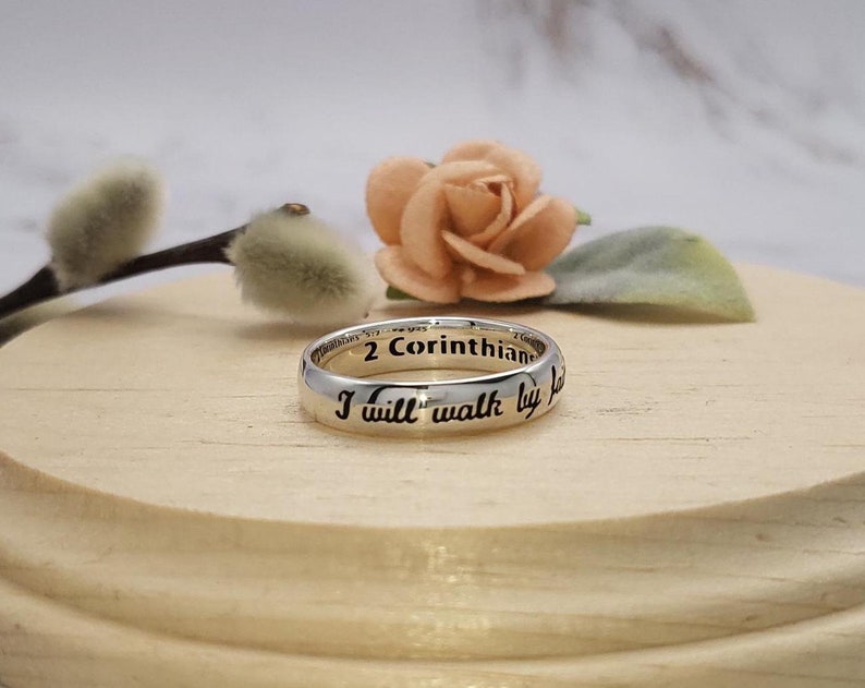 Puede incluir: Un anillo de plata con la inscripci&oacute;n "2 Corintios 5:7 Andar&eacute; por fe" grabada alrededor de la banda.