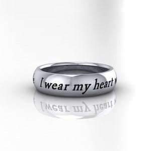 May include: A silver band ring with the inscription "I wear my heart on my sleeve" engraved on the outside.