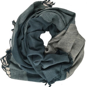 May include: A teal and gray striped scarf with fringed edges. The scarf is folded and rolled into a circle.