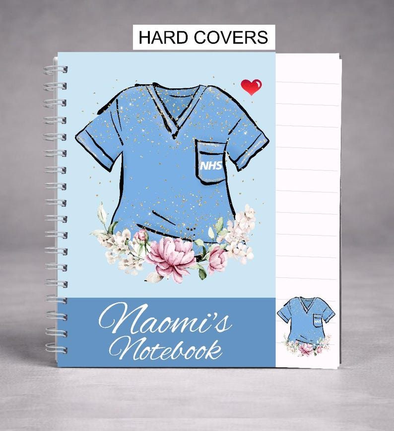 May include: A spiral-bound notebook with a light blue cover featuring a stylized illustration of a medical scrub top. The design includes a red heart, floral accents, and the text "Naomi's Notebook". The top of the notebook reads "HARD COVERS".