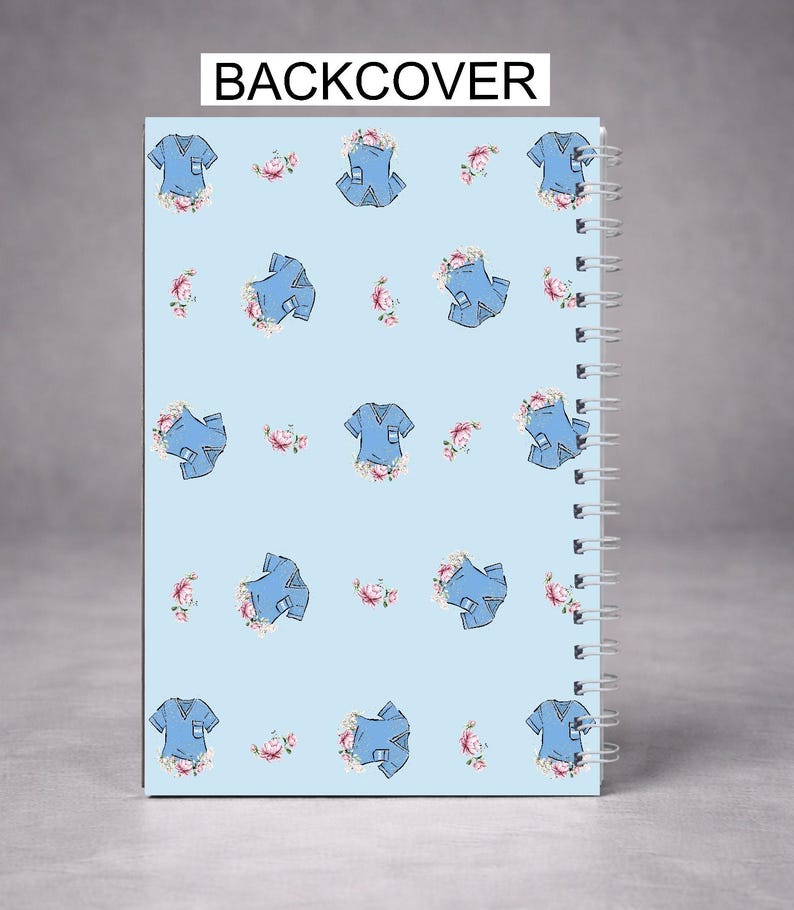 May include: A spiral-bound notebook with a light blue cover featuring a pattern of blue scrubs and pink floral accents. The text "BACKCOVER" is printed at the top. The notebook is designed for note-taking and journaling.