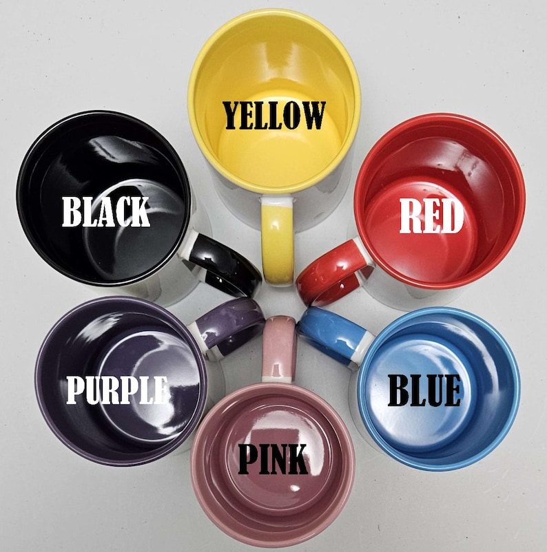 May include: Six ceramic mugs in different colors, including black, yellow, red, purple, pink, and blue. Each mug has the color name written in white letters on the inside.