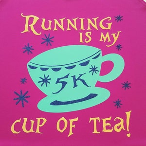 May include: Pink tank top with gold glitter text that reads "Running is my 5K cup of tea!"  The text is surrounded by small white stars. A teal blue teacup with a white rim and a white 5K inside is in the center of the shirt.