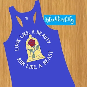 May include: A royal blue tank top with a racerback design. The front features a graphic of a stained-glass rose inside a bell jar, with the text "LOOK LIKE A BEAUTY, RUN LIKE A BEAST" in white. The text "Blackbird Fly" is in the upper right corner.