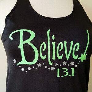 May include: Black tank top with a green "Believe" graphic and silver glitter stars. The text "13.1" is printed below the graphic.