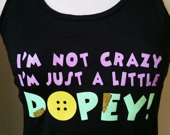 May include: Black tank top with a glittery purple and green design that says "I'm not crazy I'm just a little Dopey!" with a yellow button graphic.