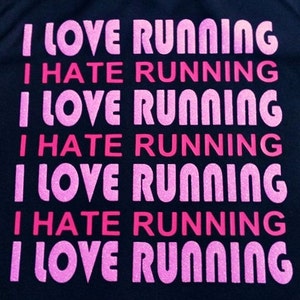 May include: A black t-shirt with the phrase "I LOVE RUNNING" and "I HATE RUNNING" repeated in pink and red glitter lettering.