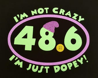 May include: A black t-shirt with a purple and green design. The design features the text "I'm not crazy I'm just Dopey!" and the number "48.6".