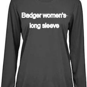 May include: A dark gray long-sleeve shirt with the text "Badger women's long sleeve" in white. The shirt has a crew neck and a small logo near the neckline. The fabric appears to be a lightweight material.