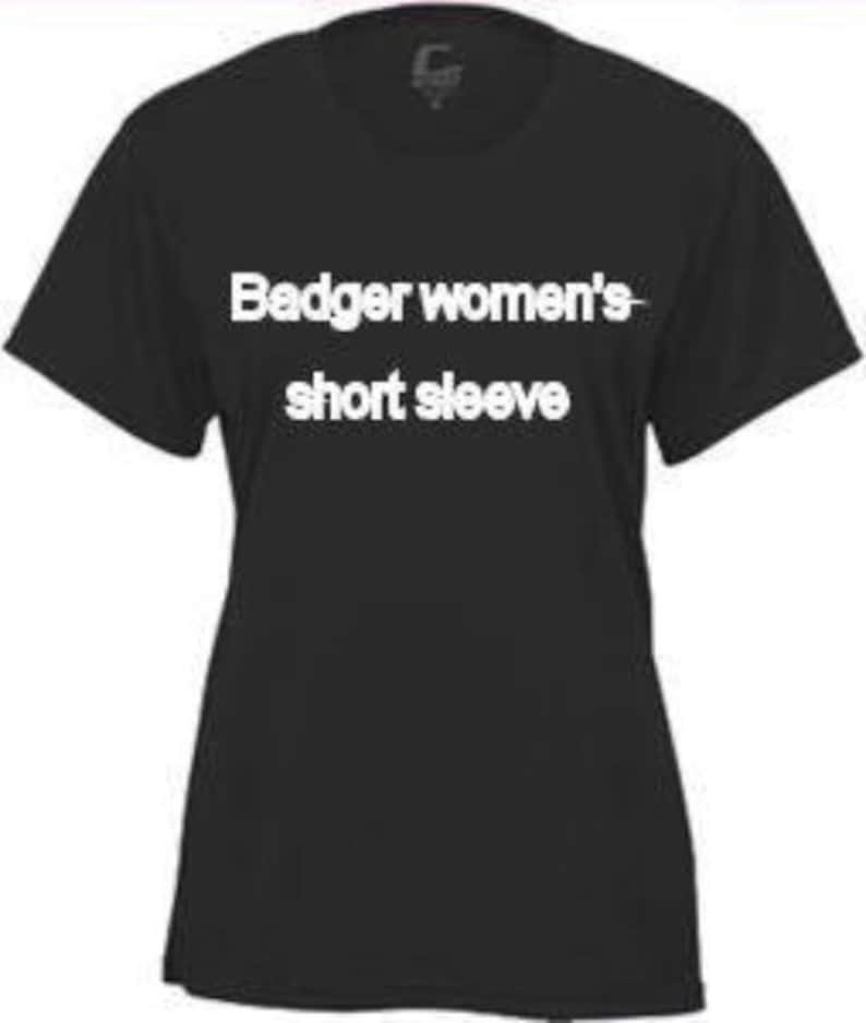 May include: Black short-sleeve t-shirt with white text that reads "Badger women's short sleeve". The shirt has a crew neck and short sleeves. The fabric appears to be a soft, lightweight material.