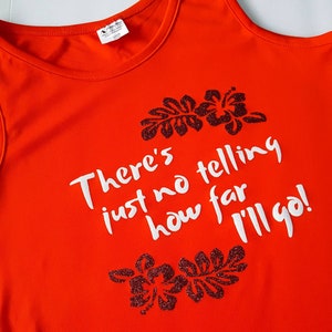 May include: Orange tank top with a white graphic that says "There's just no telling how far I'll go!" with black glitter hibiscus flowers on either side of the text.
