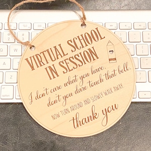 May include: A round wooden sign with the text "Virtual School in Session" and a pencil icon. The sign also includes the text "I don't care what you have. Don't you dare touch that bell. Now turn around and slowly walk away. Thank you."