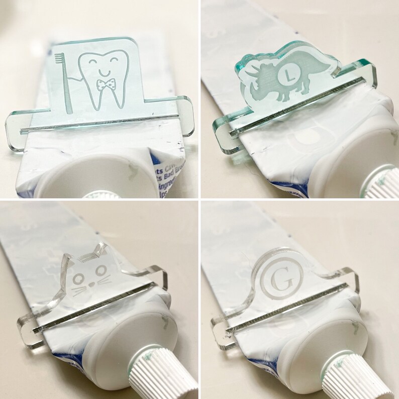May include: Four clear plastic toothpaste squeezers with different designs. The designs include a tooth with a toothbrush, a dinosaur, a cat, and a letter G. Each squeezer is attached to a tube of toothpaste.