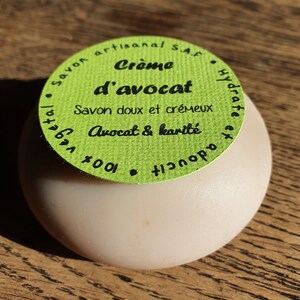 May include: A green round soap container with a white label that reads "Cr&egrave;me d'avocat Savon doux et cr&eacute;meux Avocat & karit&eacute; 14001 Hydrate et adoucit"