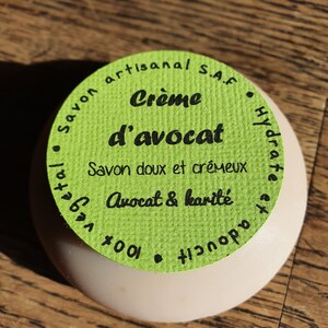 May include: A green and white round soap bar with the text "Savon artisanal S.A.F. Cr&egrave;me d'avocat Savon doux et cr&eacute;meux Avocat & karit&eacute; 100%"